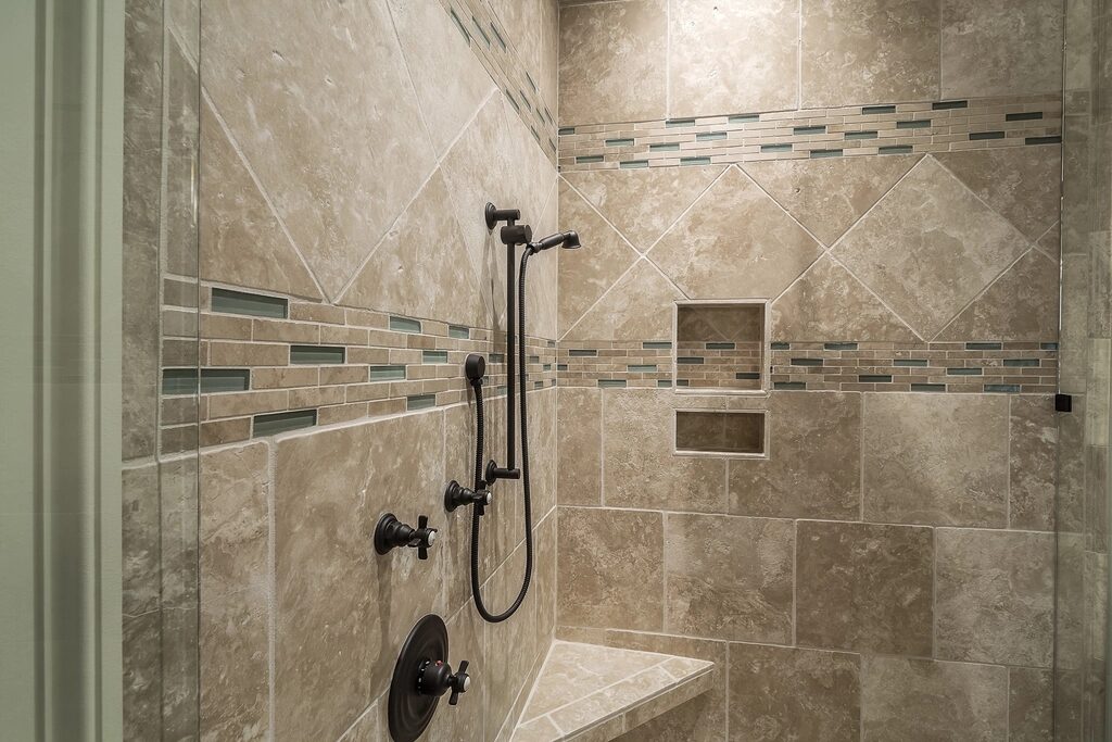 Indicative reference: a fully tiled shower enclosure with recessed niches and a mosaic feature band